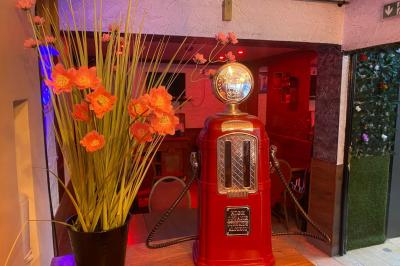 Miniature Location salle Paris 11 (Paris) - Bar de l'Hôtel de la Paix #9 Façade d'un café avec une table extérieure en bois, revêtement en gazon synthétique et intérieur éclairé visible.