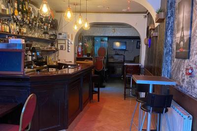 Miniature Location salle Paris 11 (Paris) - Bar de l'Hôtel de la Paix #11 Façade d'un café avec une table extérieure en bois, revêtement en gazon synthétique et intérieur éclairé visible.