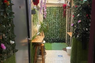 Miniature Location salle Paris 11 (Paris) - Bar de l'Hôtel de la Paix #12 Façade d'un café avec une table extérieure en bois, revêtement en gazon synthétique et intérieur éclairé visible.