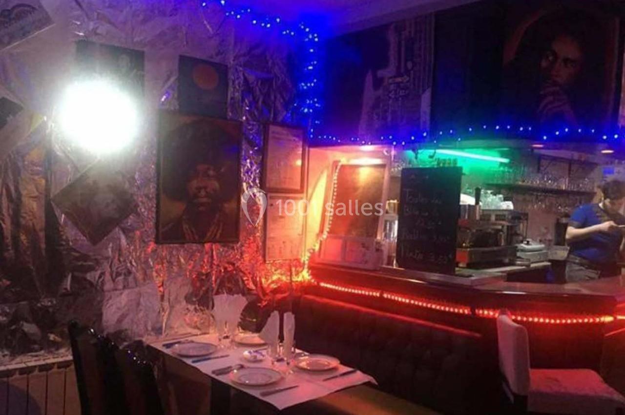 Salle de restaurant décorée avec des affiches, des guirlandes lumineuses et une table dressée pour quatre personnes.