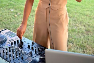 Miniature DJ Alfortville (Val-de-Marne) - Infinia #16 Personne ajustant les commandes d'une table de mixage en plein air, avec de l'herbe en arrière-plan.