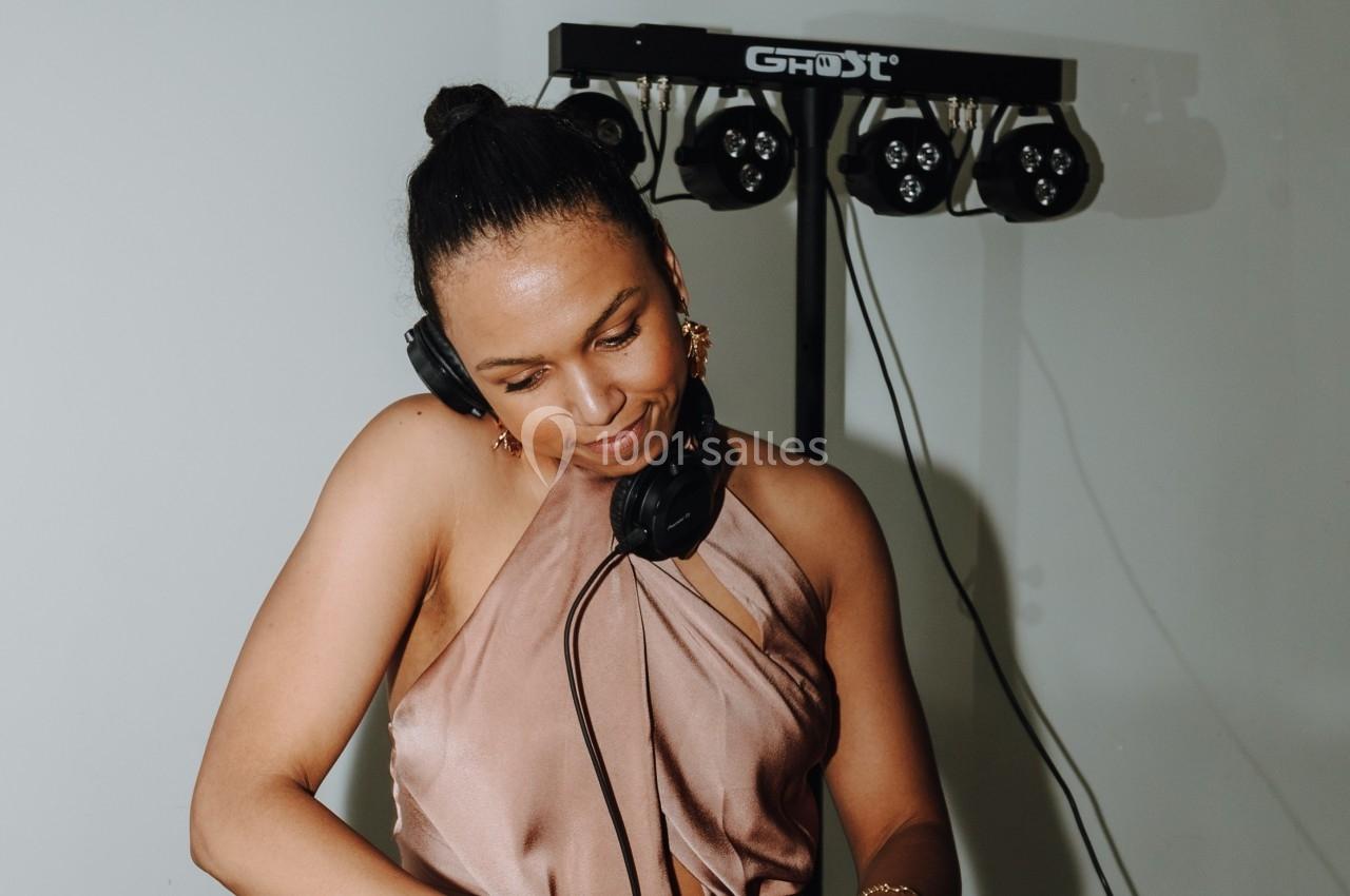 Femme portant un casque audio, concentrée sur son activité devant un équipement de sonorisation.