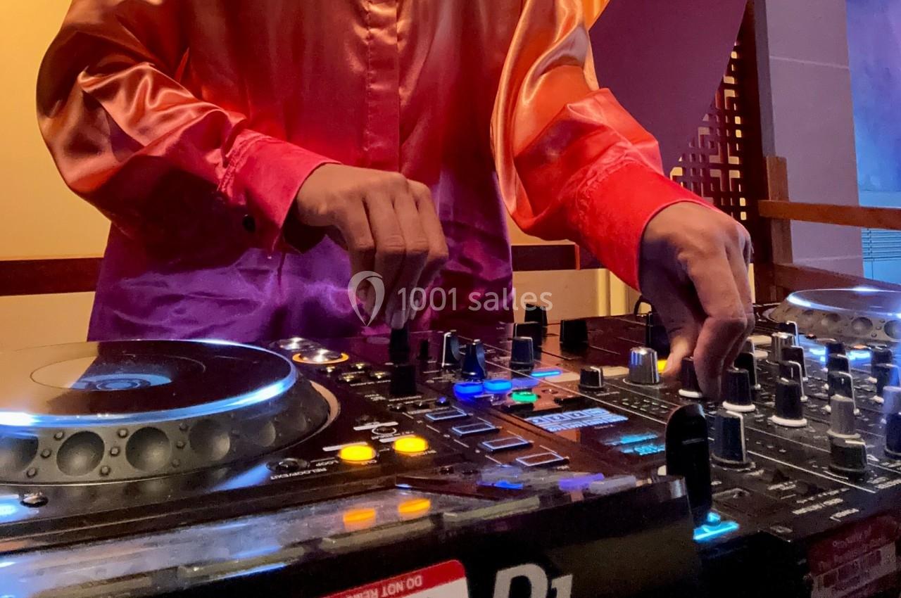 Personne utilisant une table de mixage avec des platines et des commandes lumineuses dans un environnement intérieur.