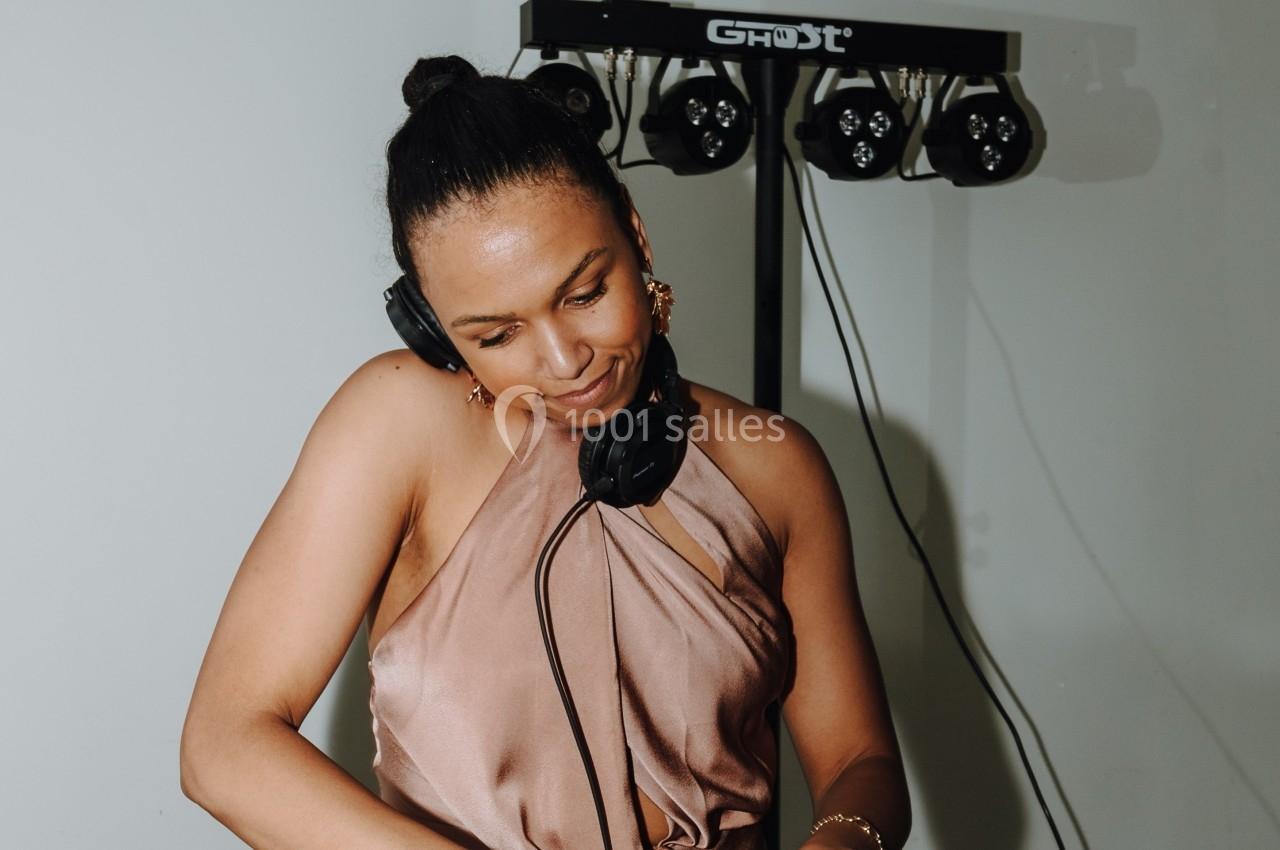 Femme portant un casque audio, mixant de la musique sur un équipement DJ dans un environnement intérieur.