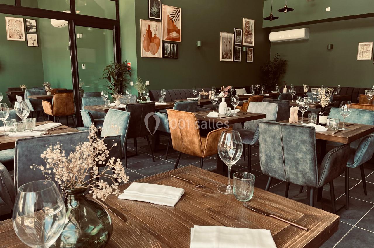 Salle de restaurant moderne avec tables en bois, chaises rembourrées, décoration murale et ambiance chaleureuse.