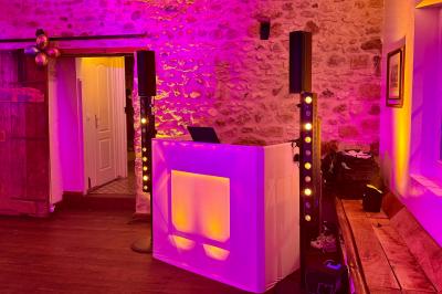 Des invités dansent joyeusement sous des lumières colorées dans une salle décorée pour une fête ou un mariage.