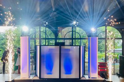 Des invités dansent joyeusement sous des lumières colorées dans une salle décorée pour une fête ou un mariage.