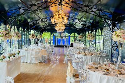 Des invités dansent joyeusement sous des lumières colorées dans une salle décorée pour une fête ou un mariage.