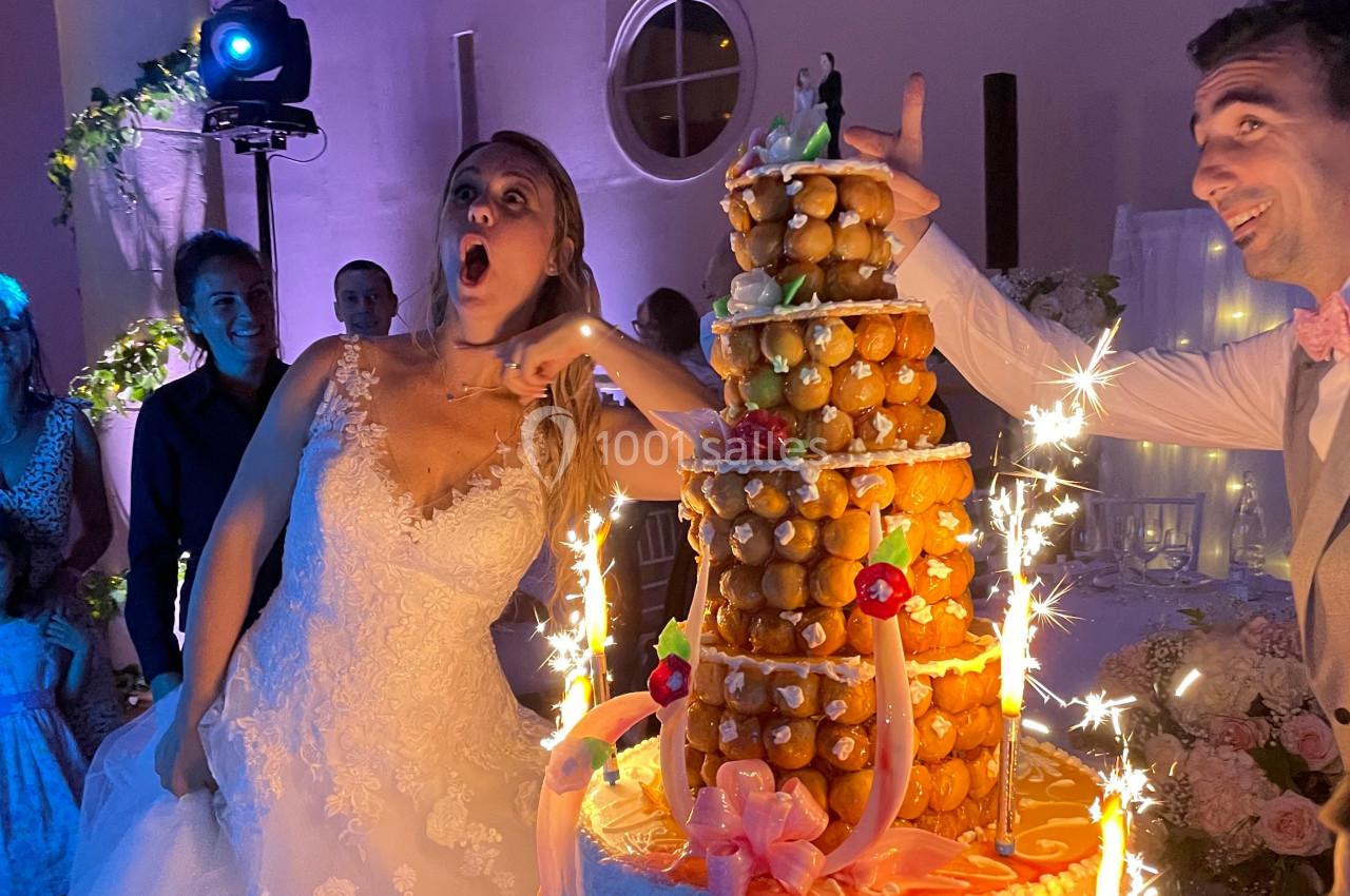 Une mariée surprise devant une pièce montée éclairée de bougies étincelantes lors d'une réception de mariage.
