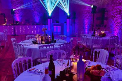Des invités dansent joyeusement sous des lumières colorées dans une salle décorée pour une fête ou un mariage.