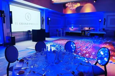 Des invités dansent joyeusement sous des lumières colorées dans une salle décorée pour une fête ou un mariage.