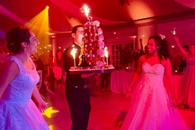 Des invités dansent joyeusement sous des lumières colorées dans une salle décorée pour une fête ou un mariage.