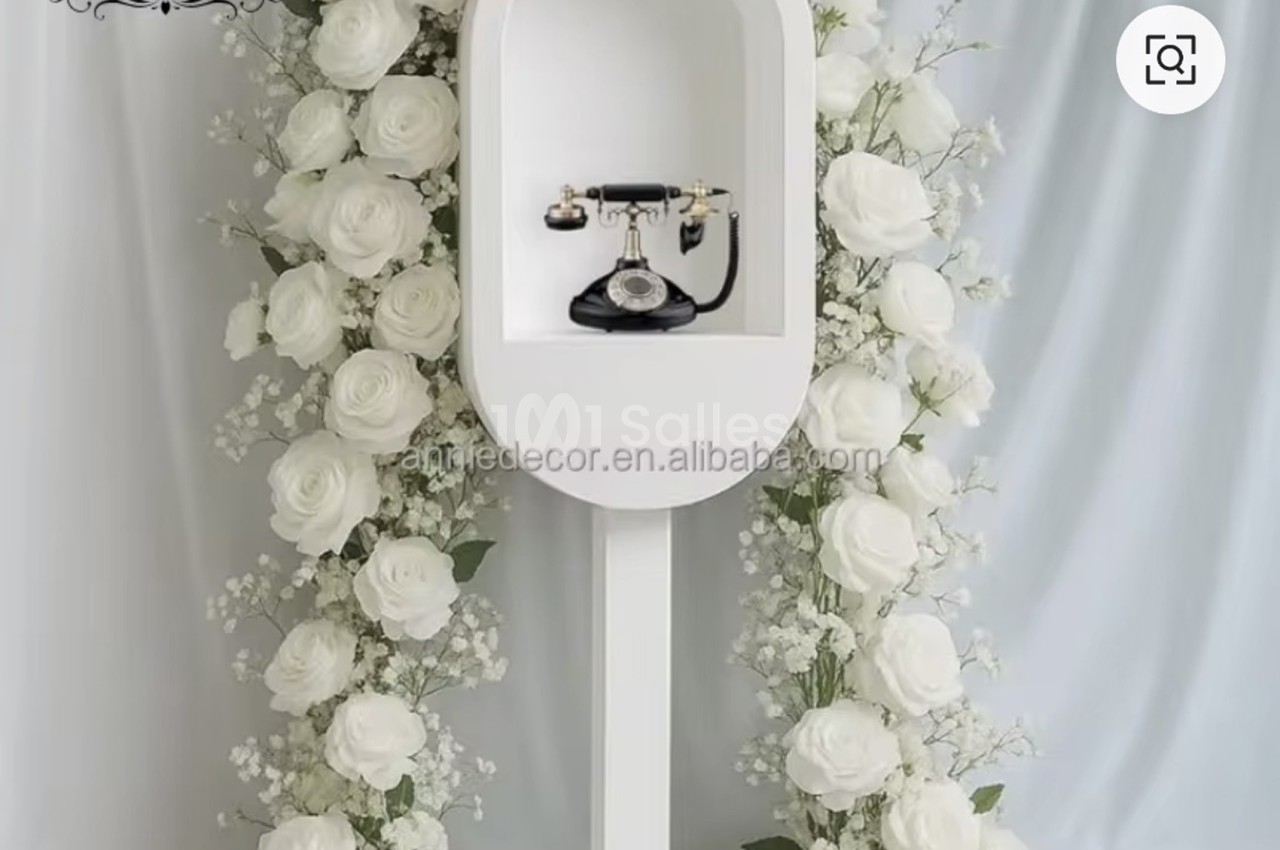 Arche blanche ornée de roses blanches et fleurs blanches des deux côtés, téléphone noir vintage suspendu au centre.
