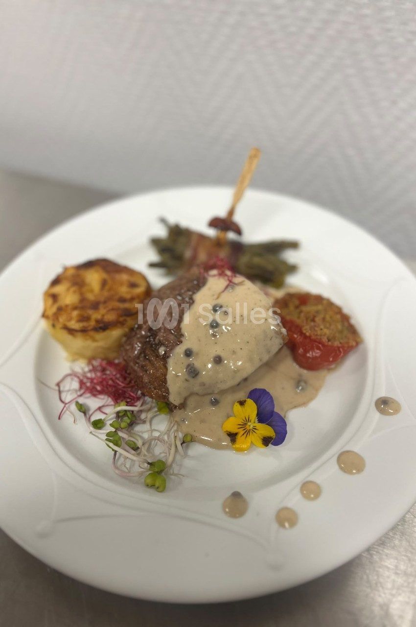 Assiette de gastronomie avec viande sauce crème, légumes rôtis, microgreens et fleurs comestibles.