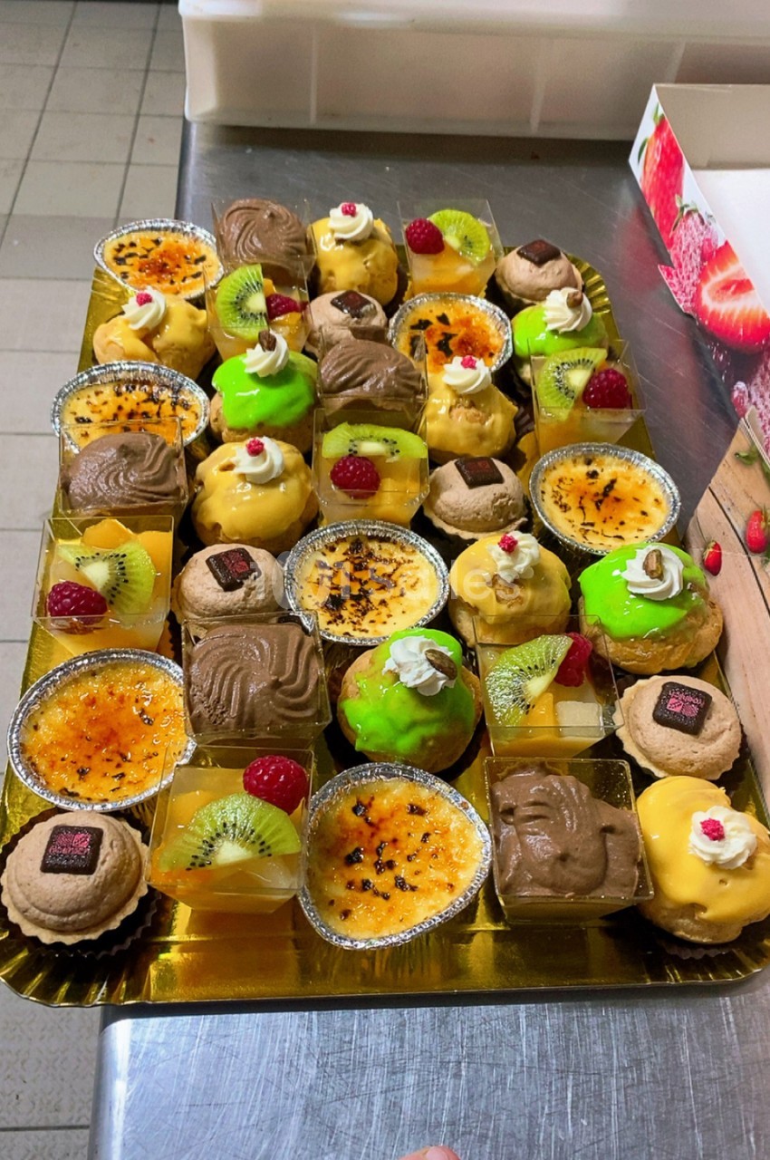 Assortiment de desserts individuels en plateau doré - tartelettes, éclairs, mousses et fruits frais.