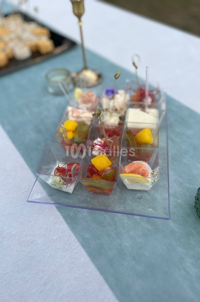 Amuse-bouches individuels en verrines sur plateau bleu - fruits, poissons et accompagnements variés.