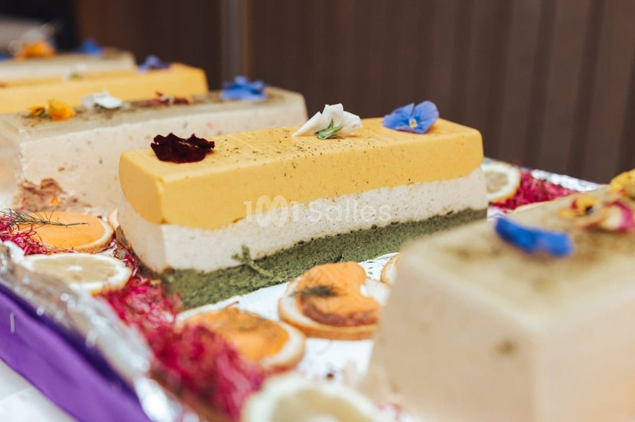 Terrines de desserts multicouches aux saveurs variées, décorées de fleurs comestibles et fruits secs.