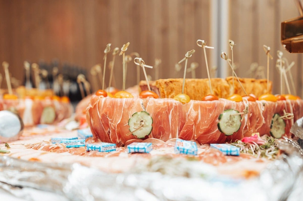 Canapés au jambon de Parme garnis de tranches de concombre et de piques dorées, sur buffet de réception.