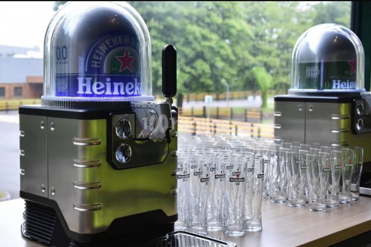 Deux tireuses à bière Heineken avec dômes lumineux bleus et verres alignés sur un comptoir en extérieur.