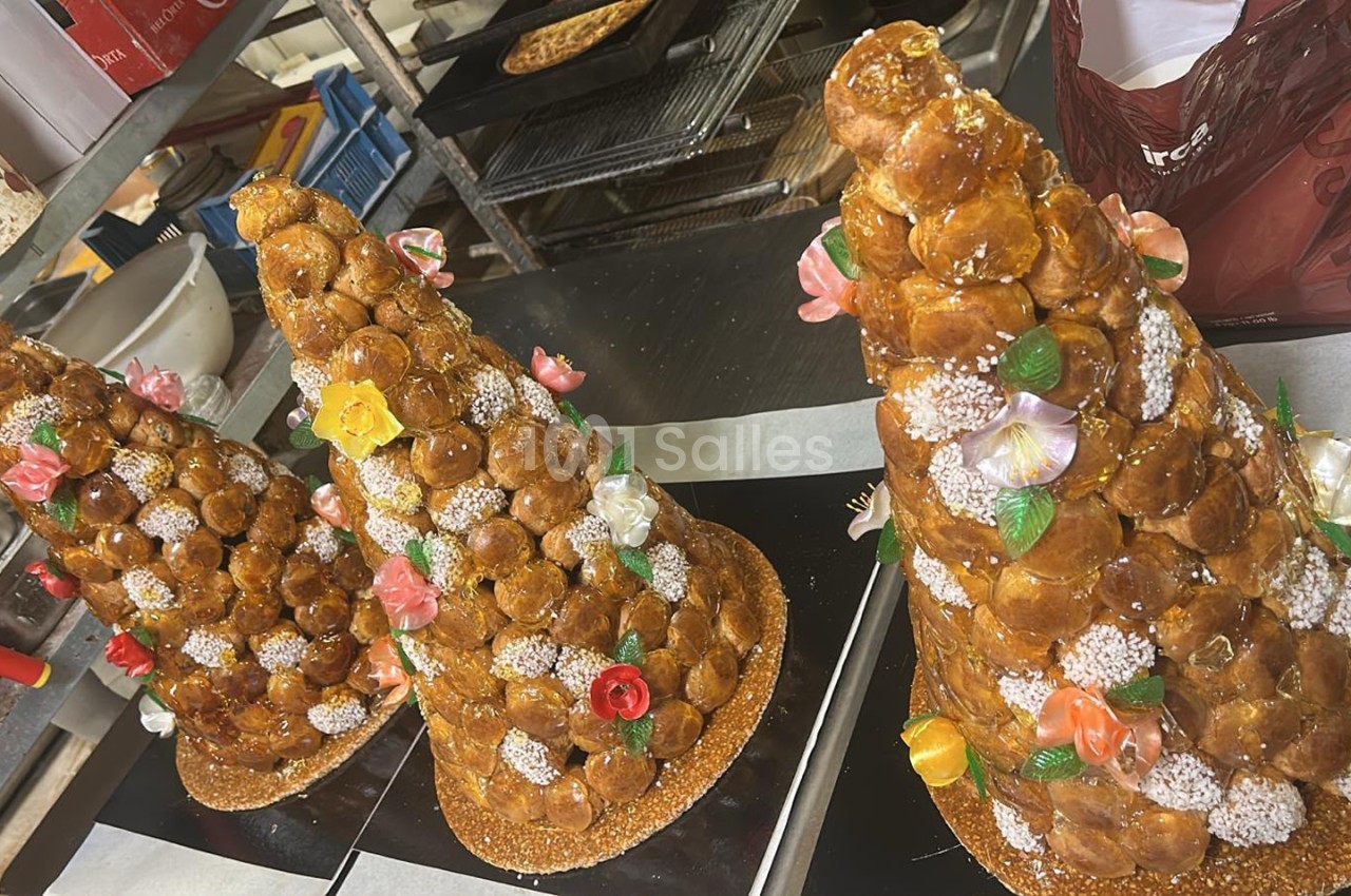 Trois pièces montées en choux décorées de fleurs colorées et sucre glace, présentées en vitrine de pâtisserie.