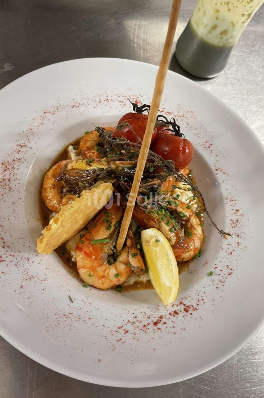 Assiette blanche avec crevettes, tomates cerises, herbes fraîches, citron et poudre de paprika.