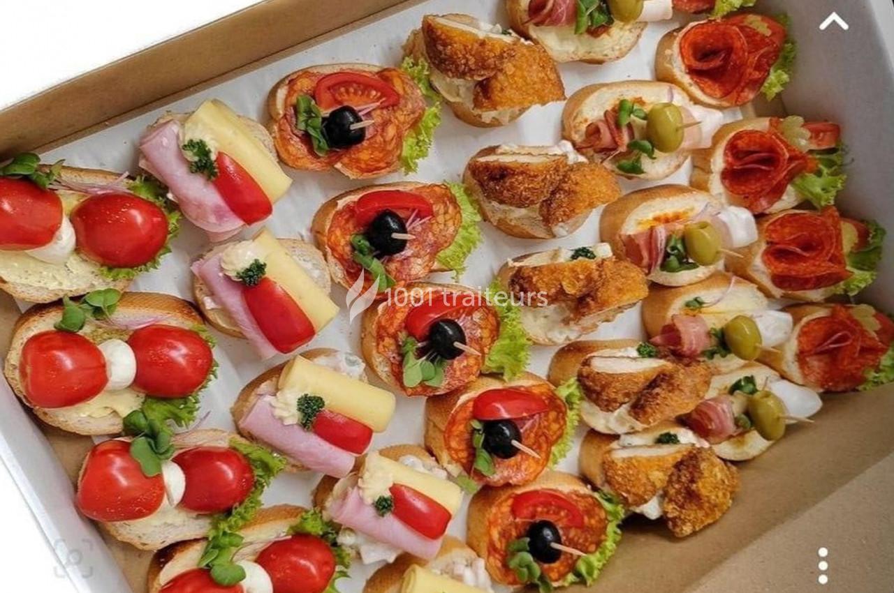 Plateau de canapés variés garnis de légumes, charcuteries, fromages et olives, disposés sur des tranches de pain.