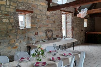 Miniature Location salle Esmery-Hallon (Somme) - La Bergerie #9 Salle de réception en pierre avec tables dressées, décorations florales et bougies, éclairée par la lumière naturelle.