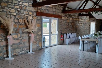 Miniature Location salle Esmery-Hallon (Somme) - La Bergerie #10 Salle de réception en pierre avec tables dressées, décorations florales et bougies, éclairée par la lumière naturelle.