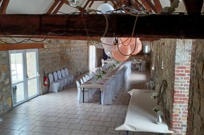 Miniature Location salle Esmery-Hallon (Somme) - La Bergerie #4 Salle de réception en pierre avec tables dressées, décorations florales et bougies, éclairée par la lumière naturelle.