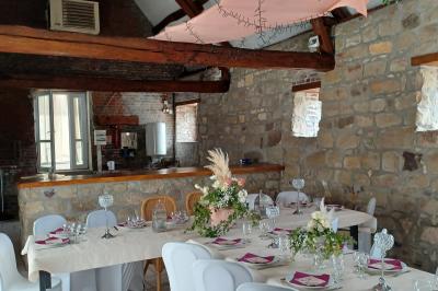 Miniature Location salle Esmery-Hallon (Somme) - La Bergerie #12 Salle de réception en pierre avec tables dressées, décorations florales et bougies, éclairée par la lumière naturelle.