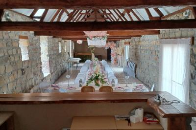 Miniature Location salle Esmery-Hallon (Somme) - La Bergerie #7 Salle de réception en pierre avec tables dressées, décorations florales et bougies, éclairée par la lumière naturelle.