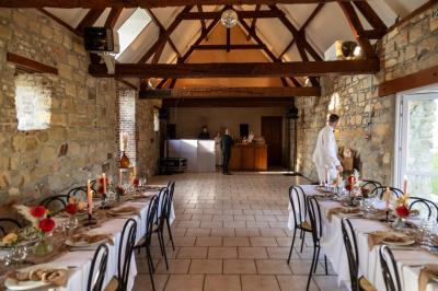 Miniature Location salle Esmery-Hallon (Somme) - La Bergerie #25 Salle de réception en pierre avec tables dressées, décorations florales et bougies, éclairée par la lumière naturelle.