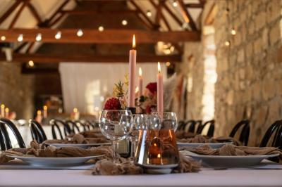 Miniature Location salle Esmery-Hallon (Somme) - La Bergerie #26 Salle de réception en pierre avec tables dressées, décorations florales et bougies, éclairée par la lumière naturelle.