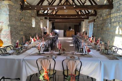 Miniature Location salle Esmery-Hallon (Somme) - La Bergerie #30 Salle de réception en pierre avec tables dressées, décorations florales et bougies, éclairée par la lumière naturelle.