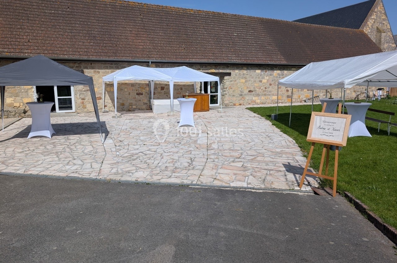 Cour pavée avec des tentes blanches installées devant un bâtiment en pierre sous un ciel dégagé.