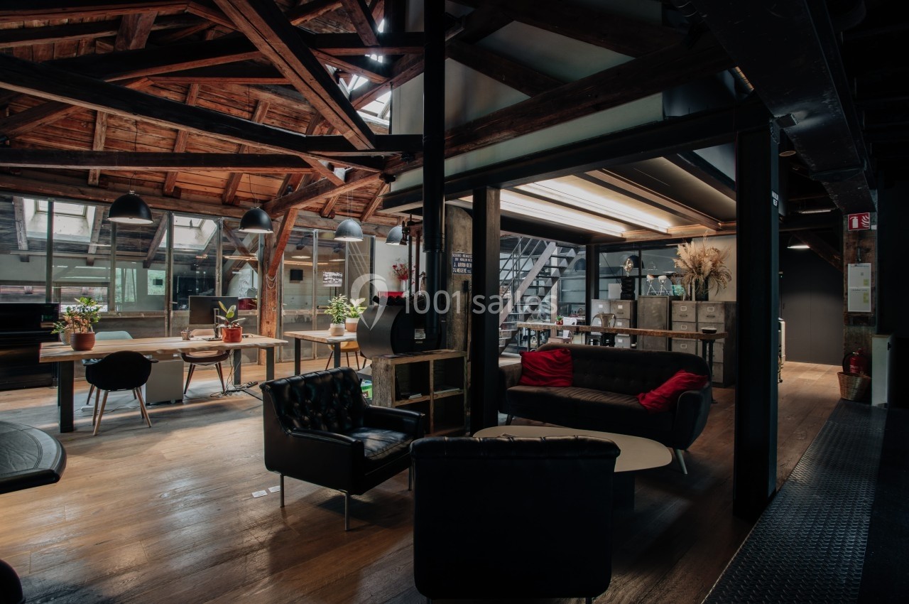 Espace intérieur moderne avec poutres apparentes, mobilier en cuir et éclairage tamisé dans un environnement chaleureux.