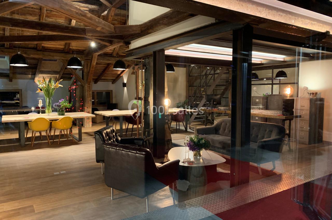 Espace intérieur moderne et chaleureux avec poutres apparentes, mobilier design et éclairage tamisé.