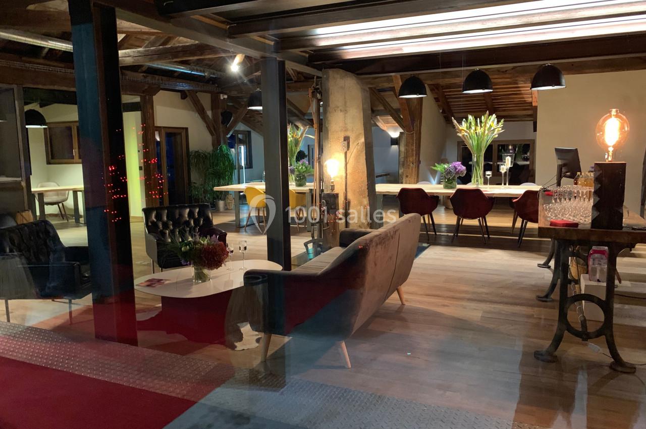 Espace intérieur chaleureux avec canapés, table en bois, éclairage tamisé et décoration florale.