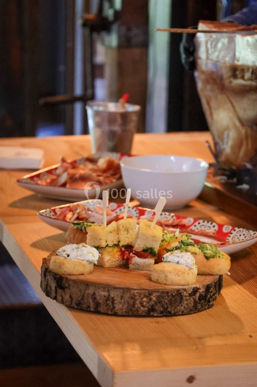 Plateau en bois avec amuse-bouches variés, disposé sur une table en bois dans un cadre rustique.