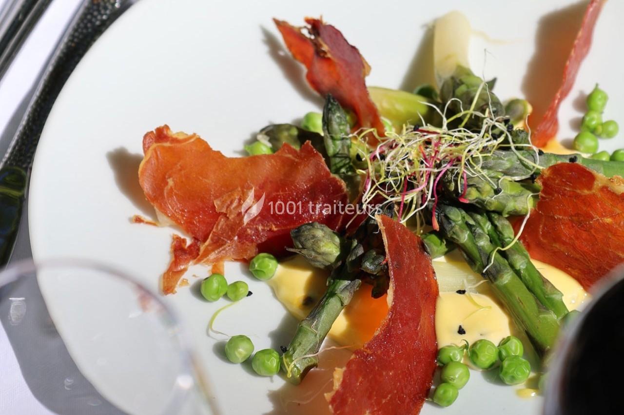 Assiette garnie d'asperges, petits pois, tranches de jambon croustillant, germes et sauce crémeuse.