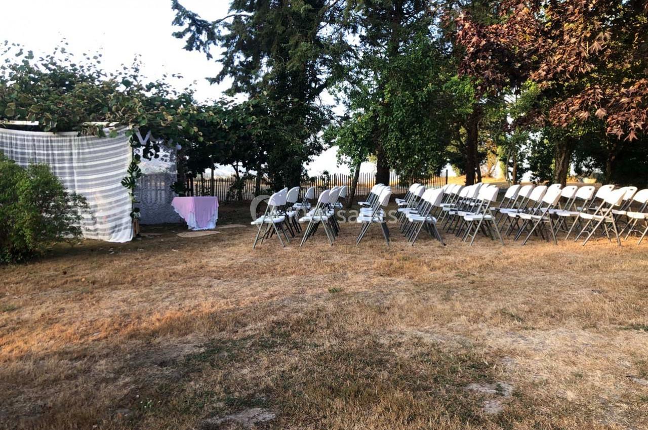 Chaises alignées en extérieur sur une pelouse sèche, face à une arche décorée pour un événement en plein air.