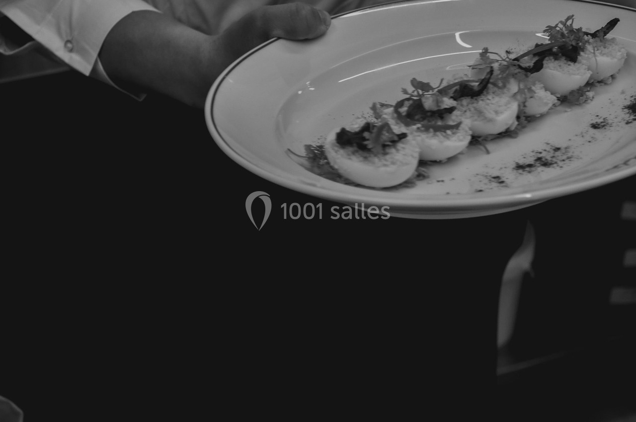 Un serveur présente une assiette contenant plusieurs œufs farcis garnis de feuilles et d'épices.
