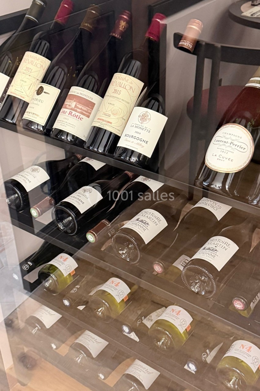 Bouteilles de vin disposées sur des étagères inclinées dans une vitrine en verre.