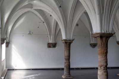 Salle voûtée illuminée par des lumières colorées, remplie de convives assis à des tables lors d'un événement.