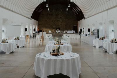 Salle voûtée illuminée par des lumières colorées, remplie de convives assis à des tables lors d'un événement.