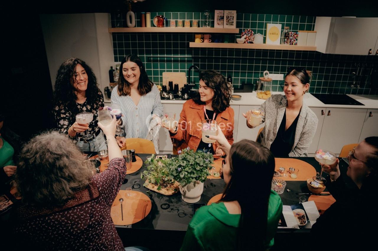Un groupe de personnes souriantes trinque autour d'une table dans une cuisine moderne avec un décor chaleureux.
