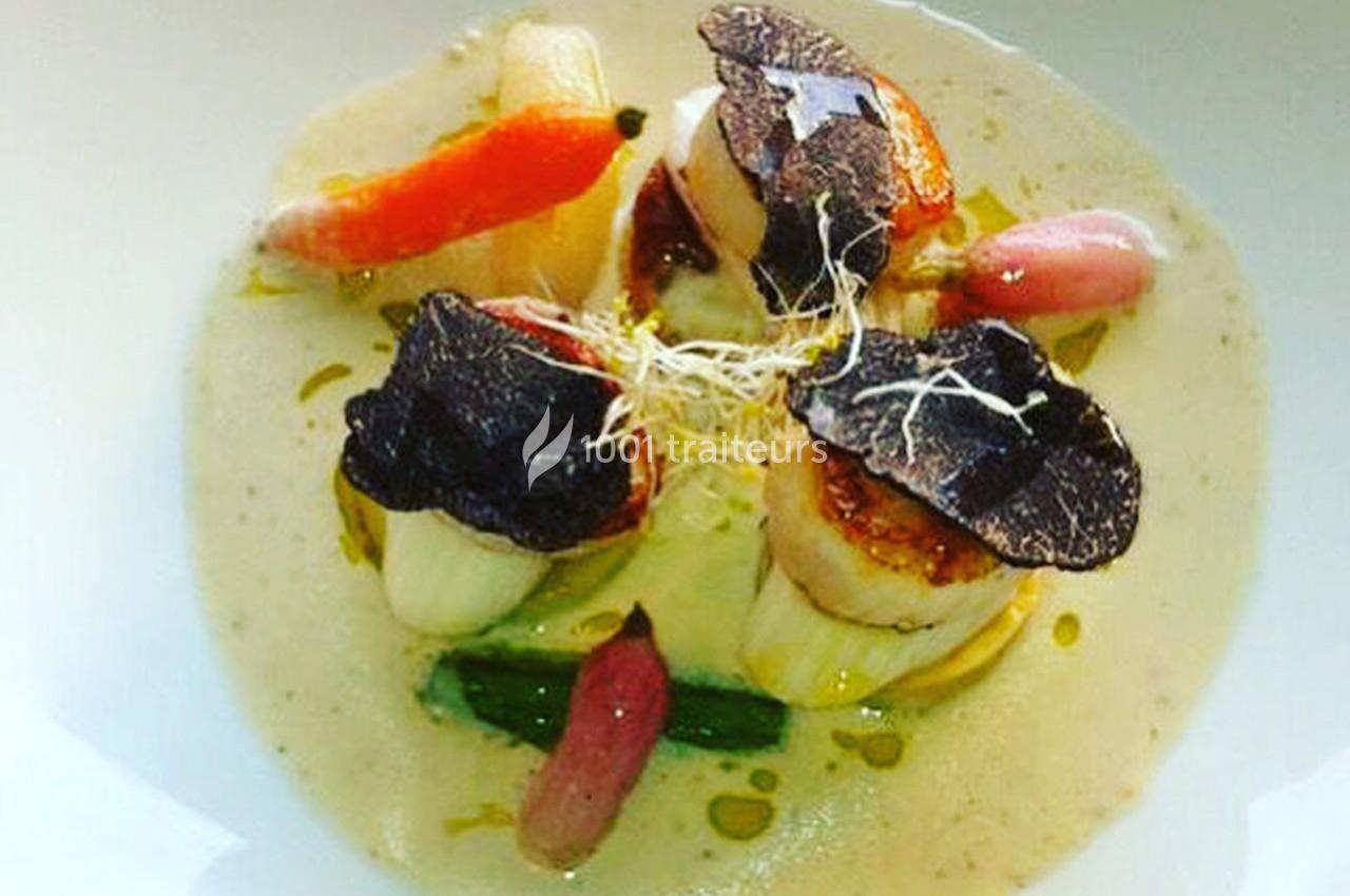 Noix de Saint-Jacques poêlées avec truffes noires, légumes colorés et sauce crémeuse, présentées dans une assiette blanche.