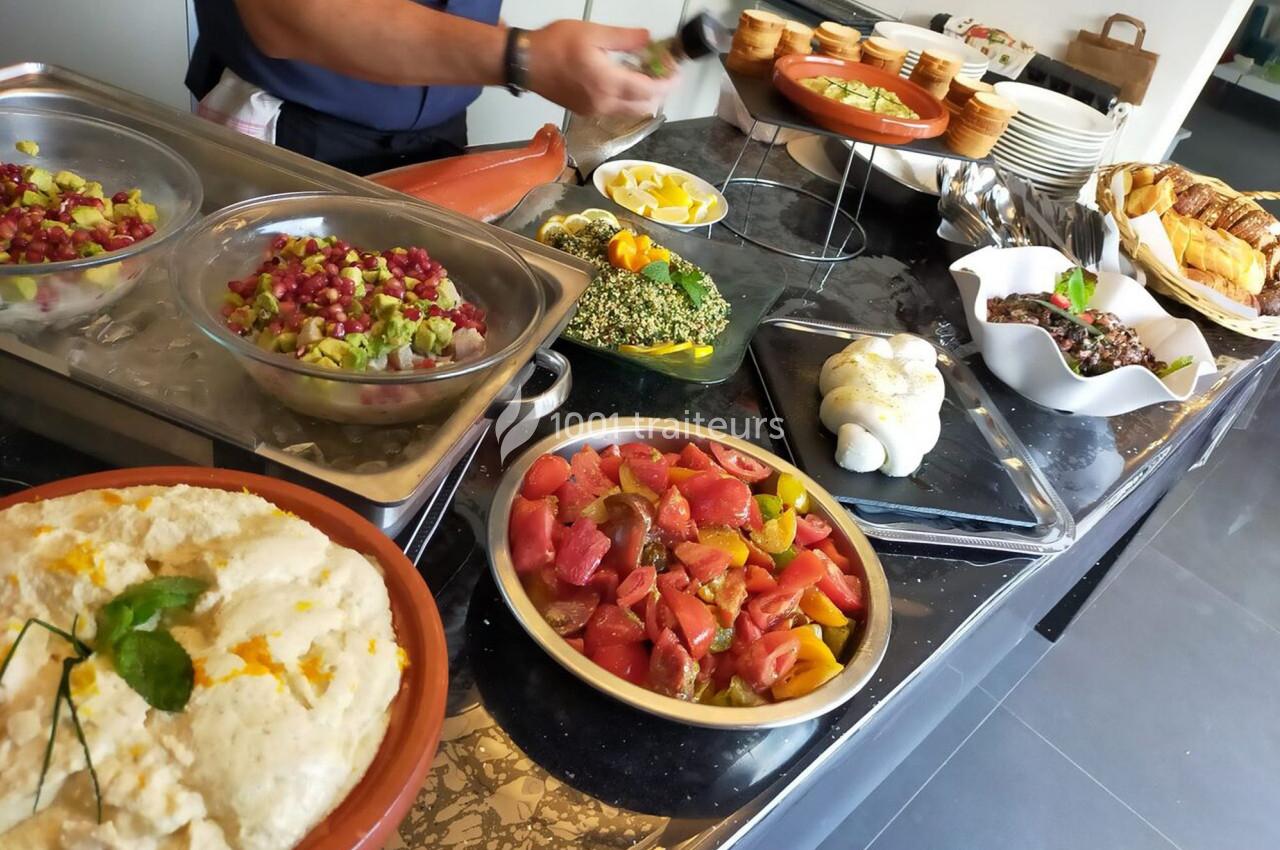 Buffet varié avec salades, pain, fromage et plats froids disposés sur un comptoir en marbre.