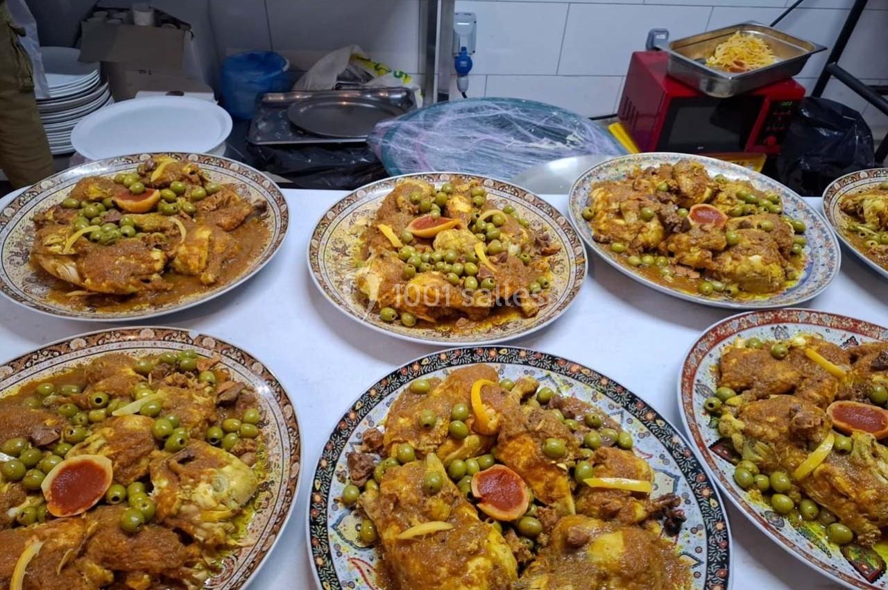 Assiettes de tajine au poulet, olives vertes et citrons confits, disposées sur une table dans une cuisine.
