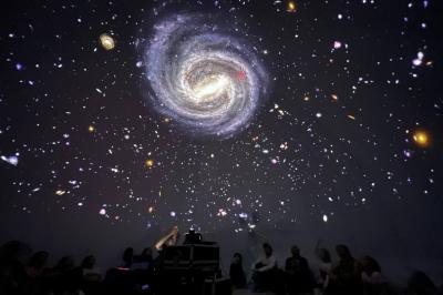 Dôme gonflable noir avec motif de galaxie, utilisé pour des projections, installé dans un gymnase.